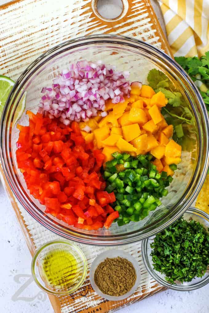 adding ingredients to bowl to make Mango Salsa