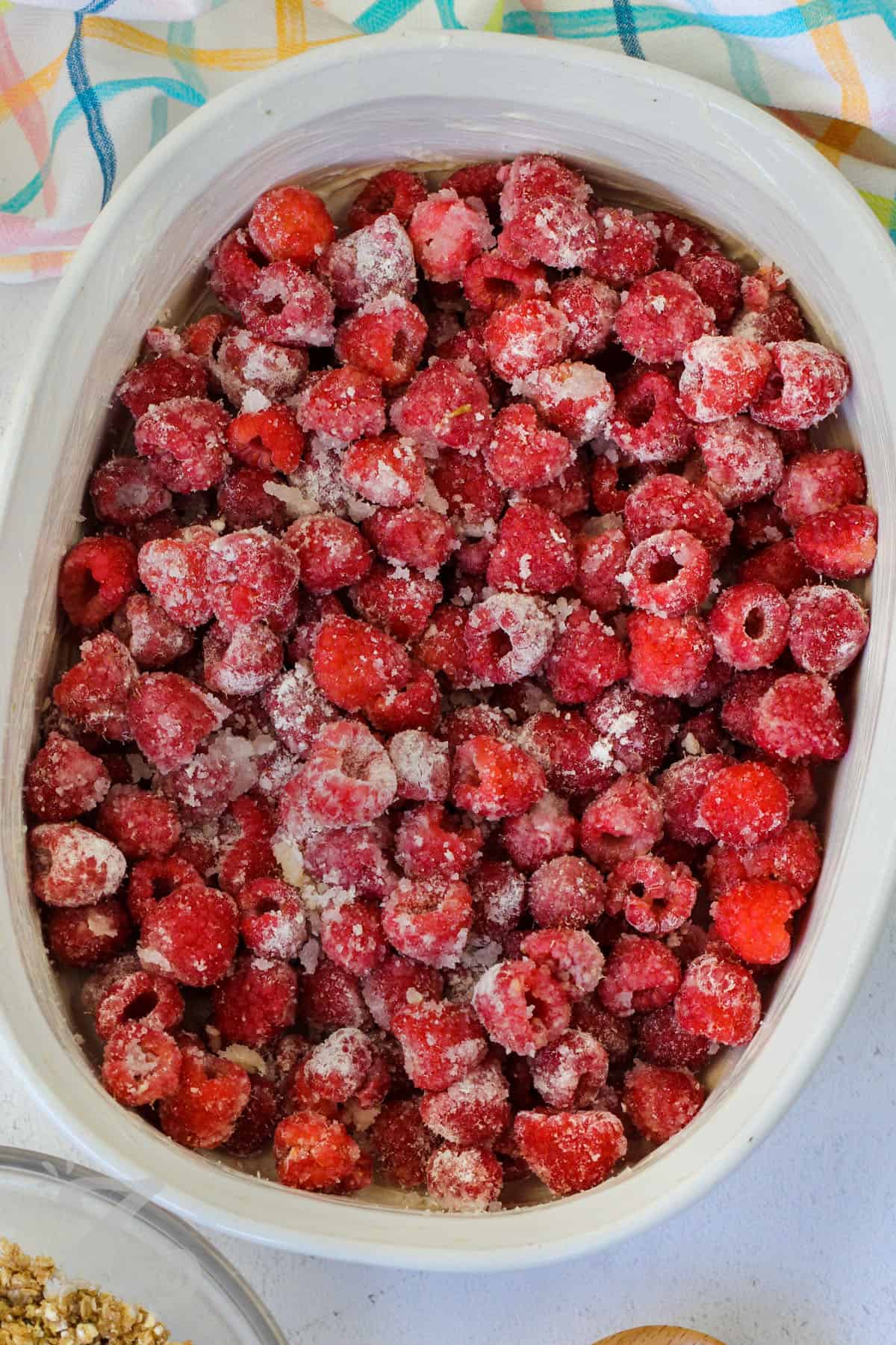 raspberries tossed with flour and sugar, in the bottom of a white baking dish, to make raspberry crisp