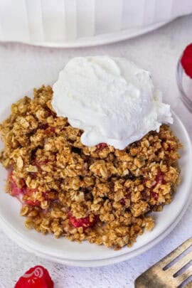 a serving of raspberry crisp with a scoop of vanilla ice cream, on a small white plate