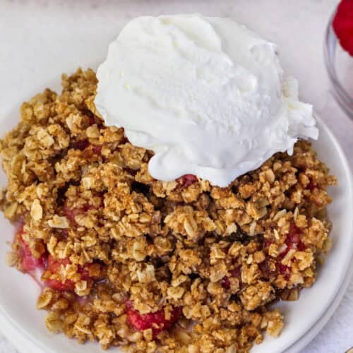 a serving of raspberry crisp with a scoop of vanilla ice cream, on a small white plate