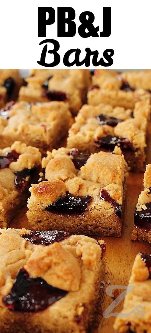 peanut butter and jelly bars cut up on a wooden cutting board with a title