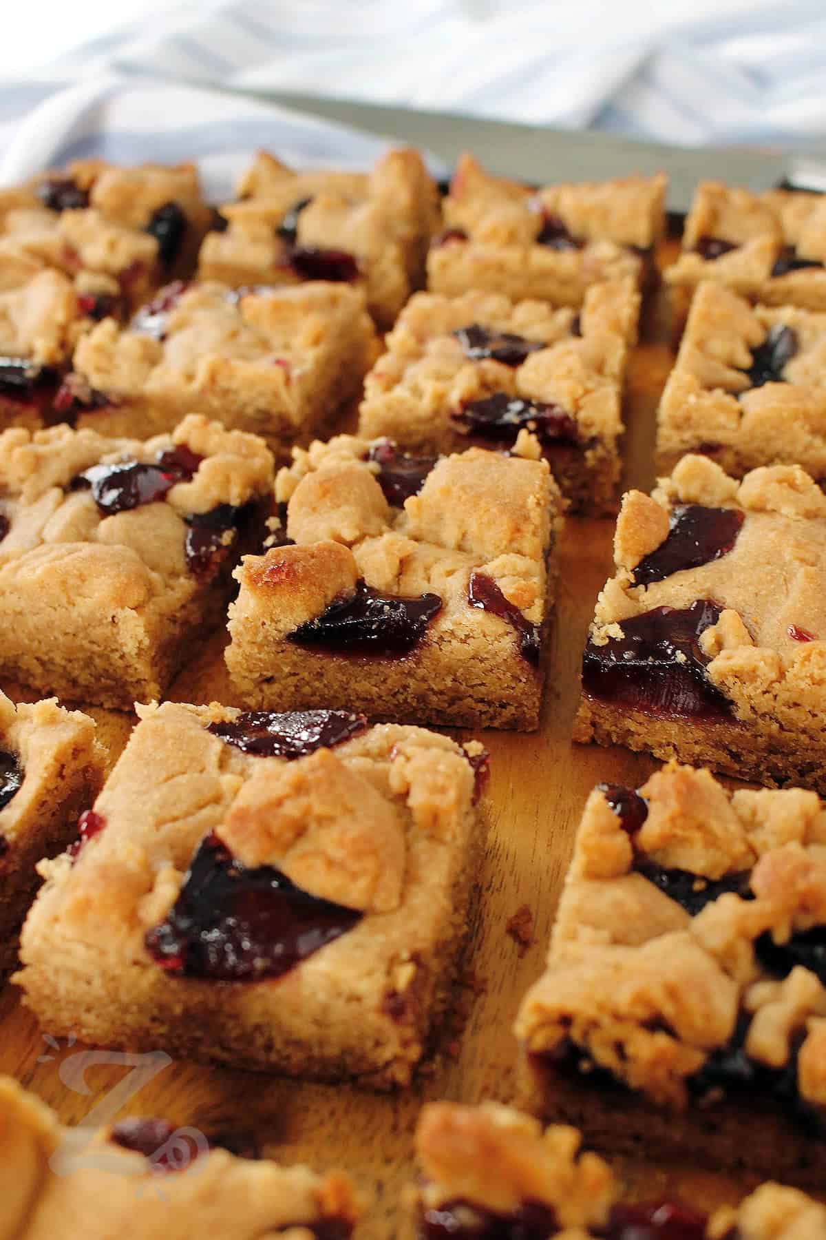 peanut butter and jelly bars cut up on a wooden cutting board