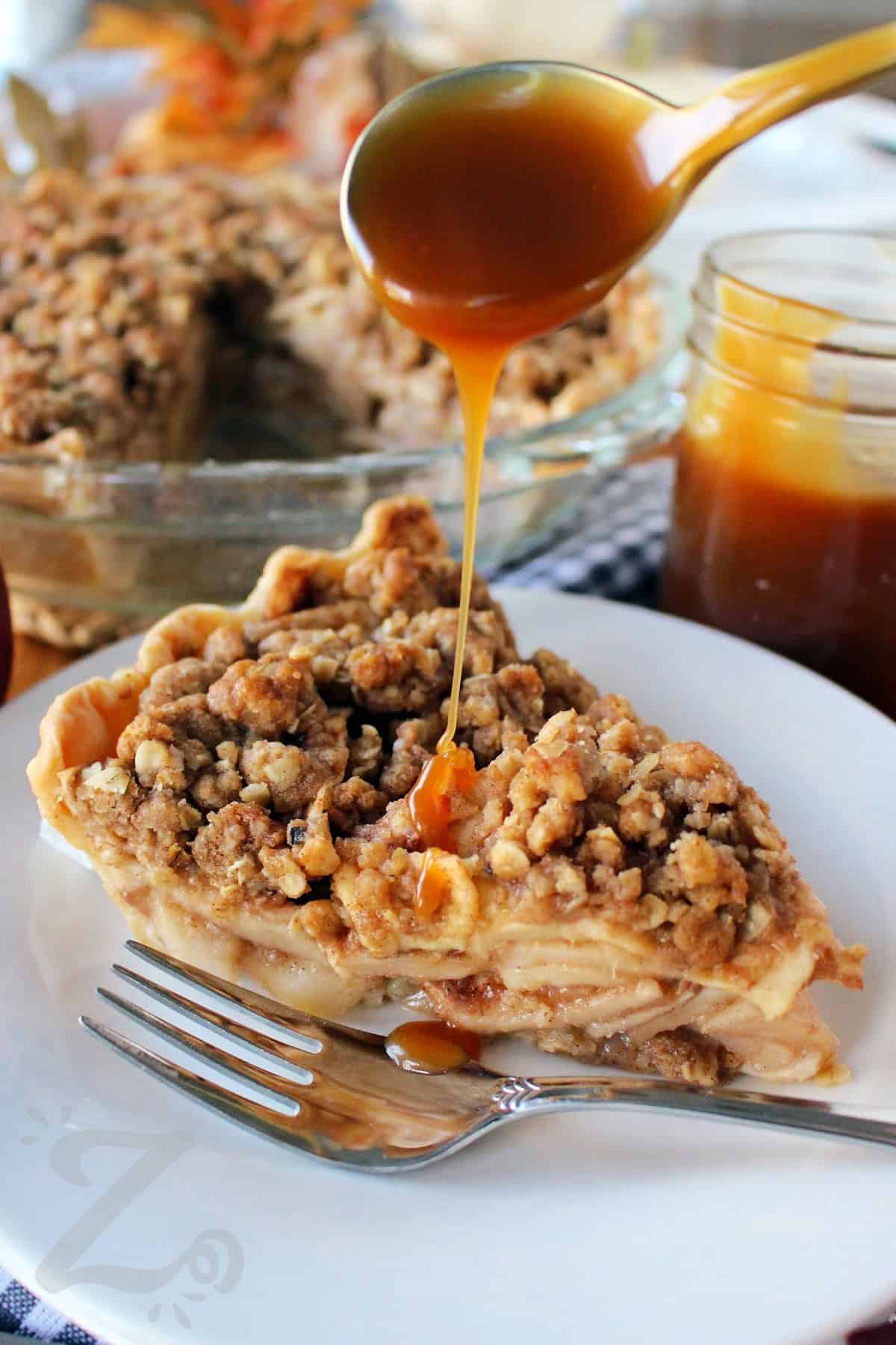 a slice of apple crumb pie with caramel sauce being poured over