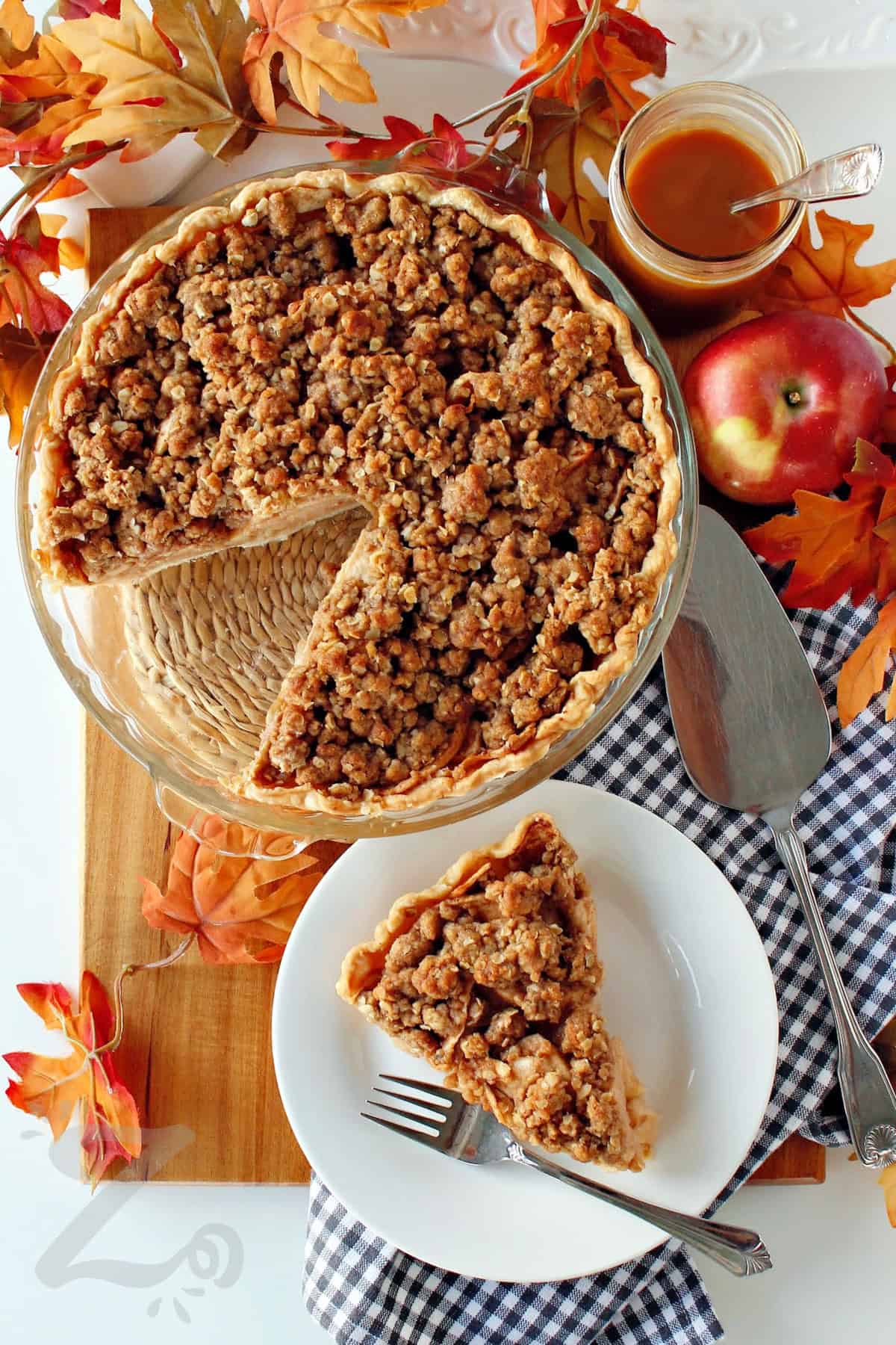 baked apple crumb pie with a slice taken out and served on a white plate