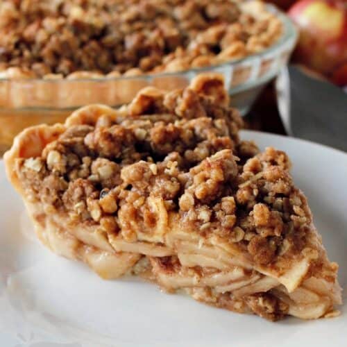 a slice of apple crumb pie on a white plate