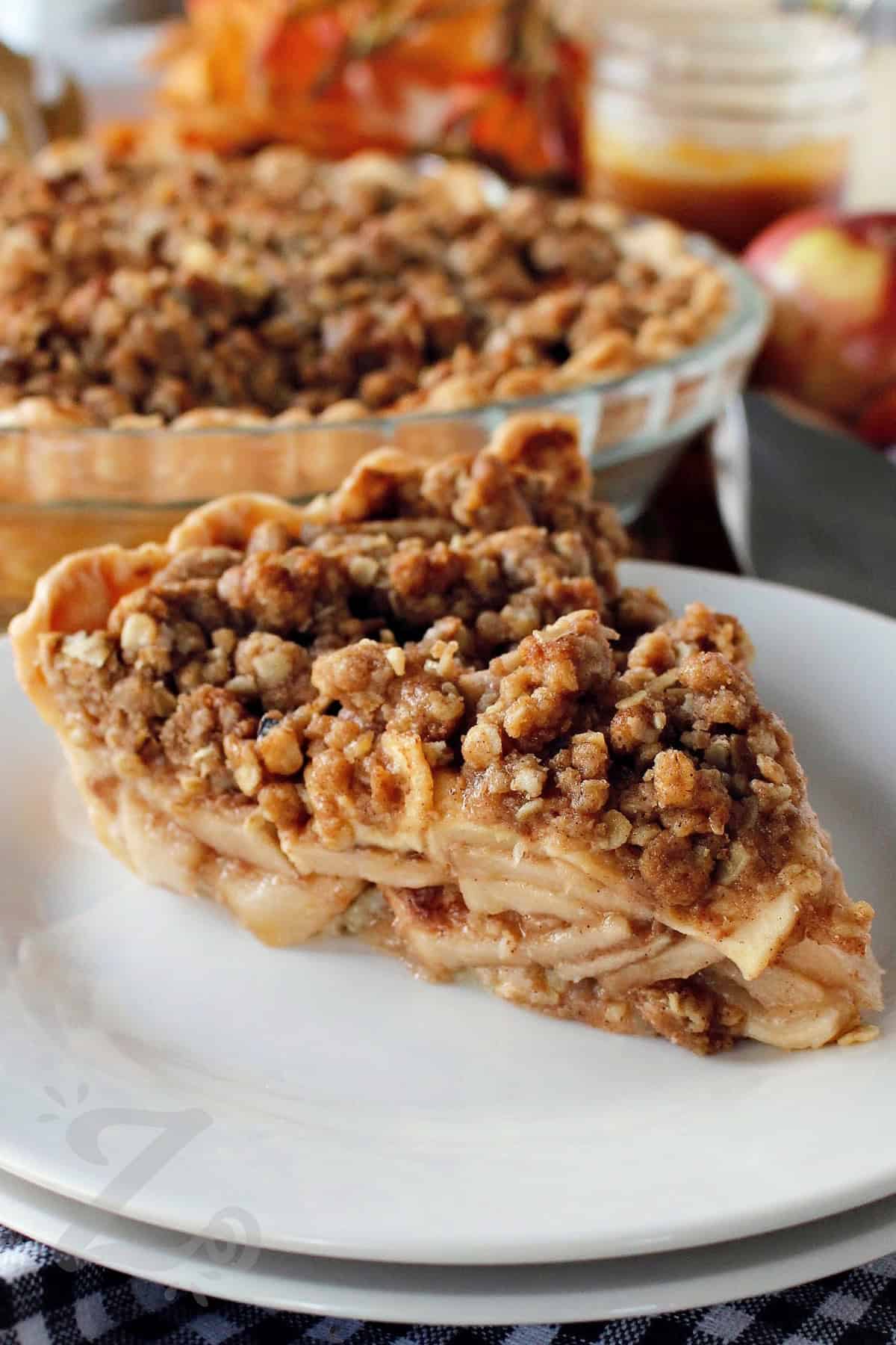 a slice of apple crumb pie on a white plate