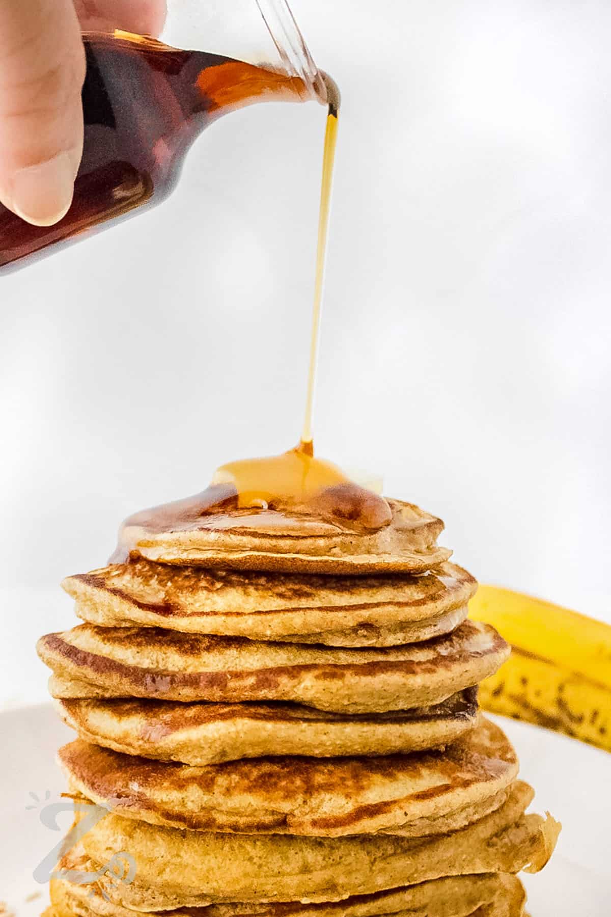 adding syrup to Banana Oat Pancakes