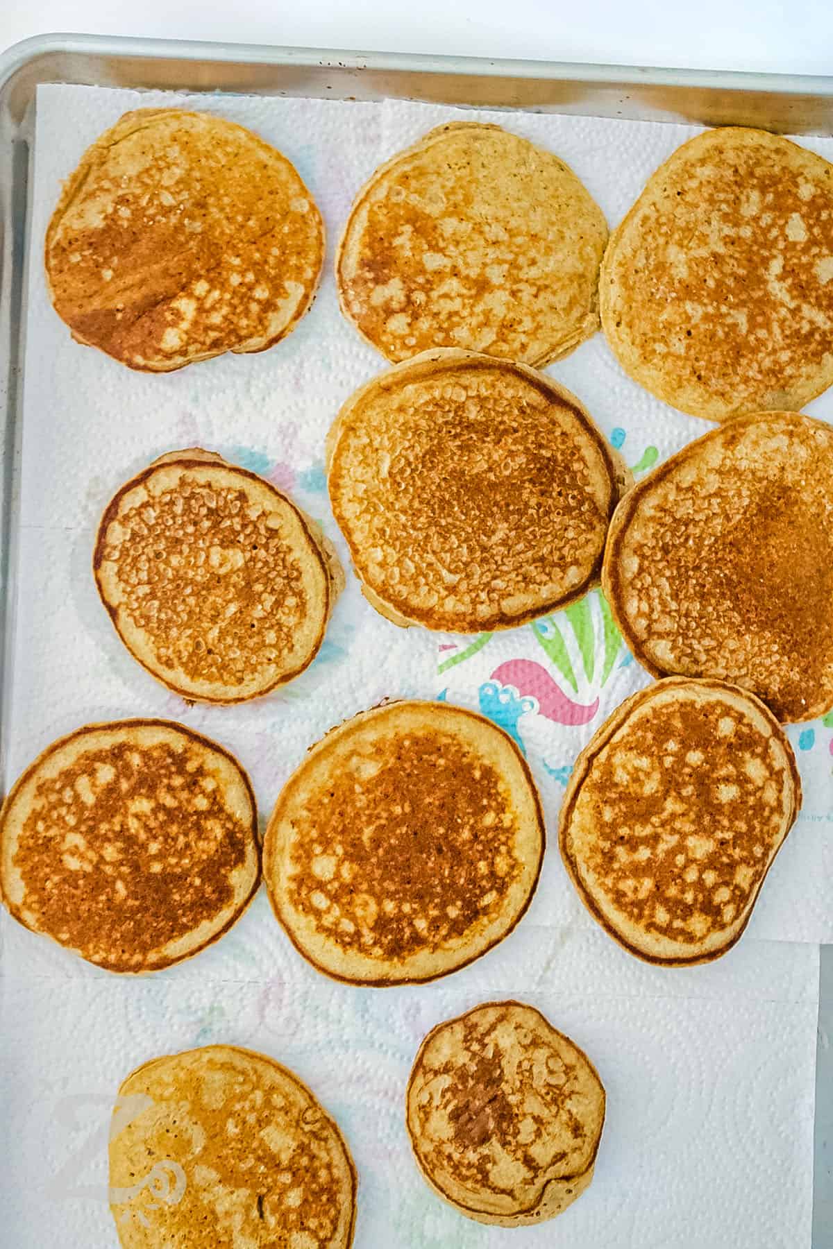 Banana Oat Pancakes cooling on paper towel on a sheet pan