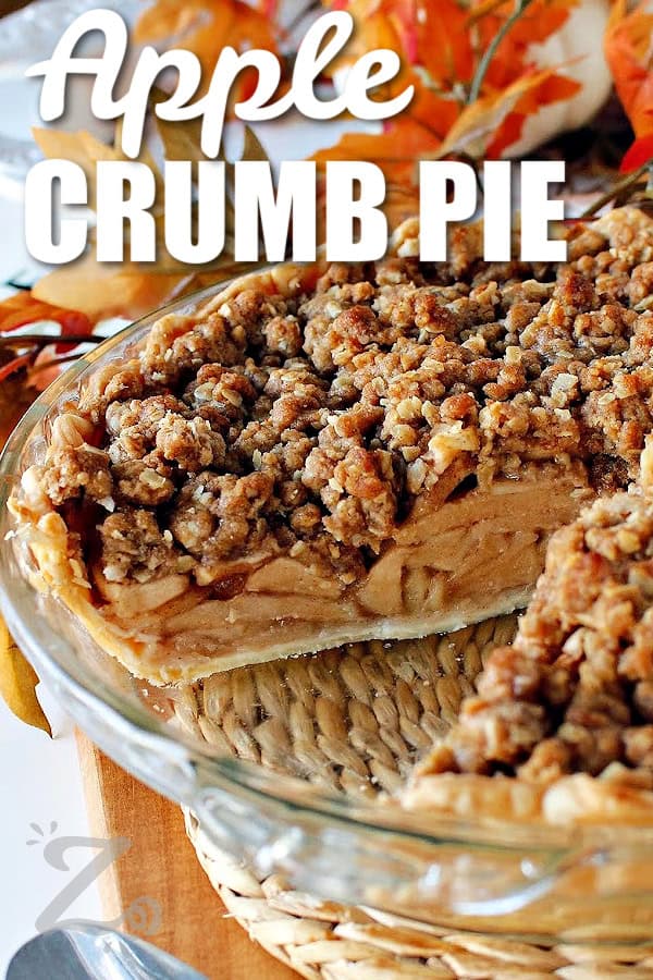 close up of baked apple crumb pie in a clear pie plate with a slice taken out, with a title