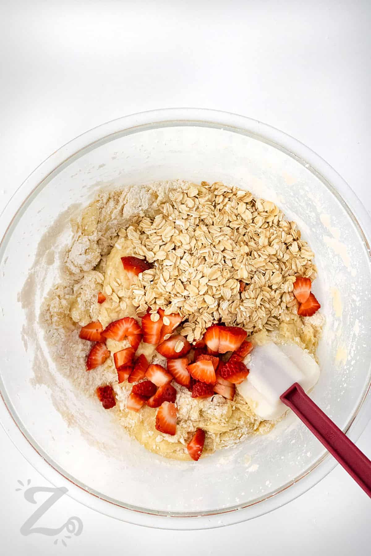 adding strawberries and oats to bowl to make Strawberry Banana Muffins