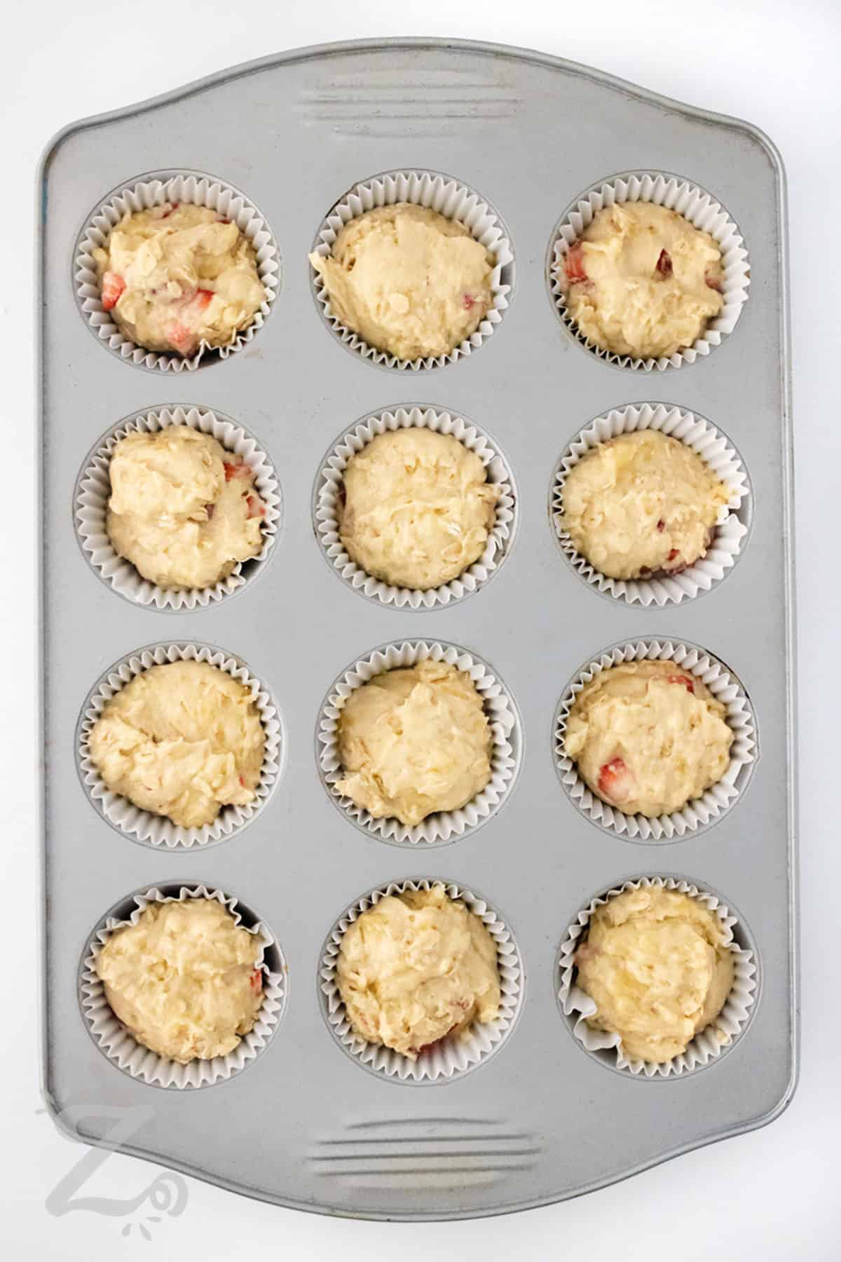 adding Strawberry Banana Muffins batter to muffin tin