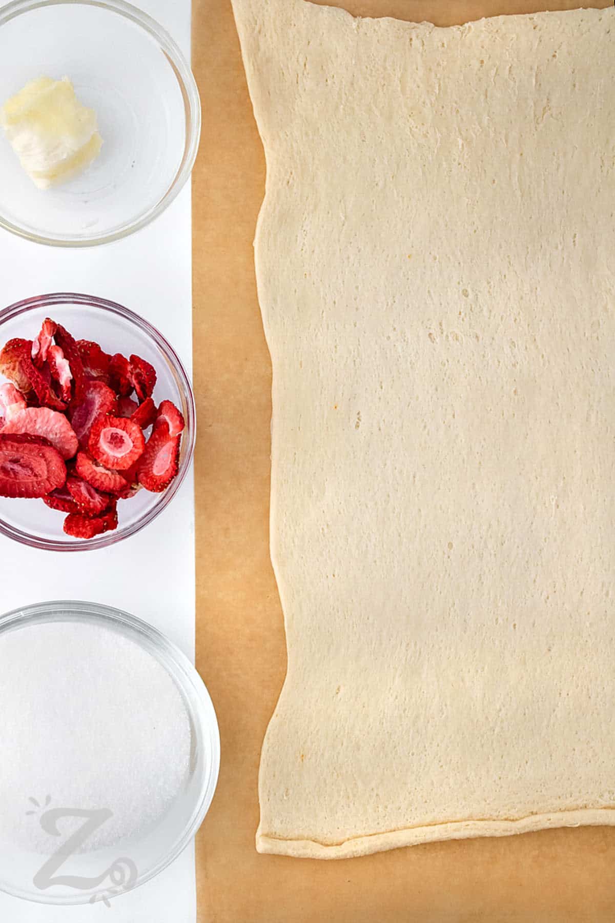 crescent roll sheet with ingredients in bowls to make Strawberry Cinnamon Rolls