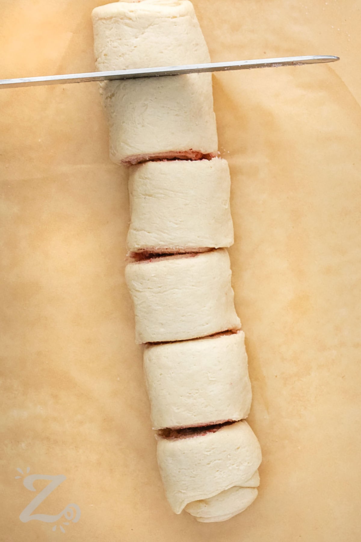 slicing roll of Strawberry Cinnamon Rolls before baking