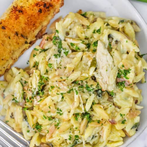 close up of Lemon Chicken Orzo on a plate with a piece of garlic toast