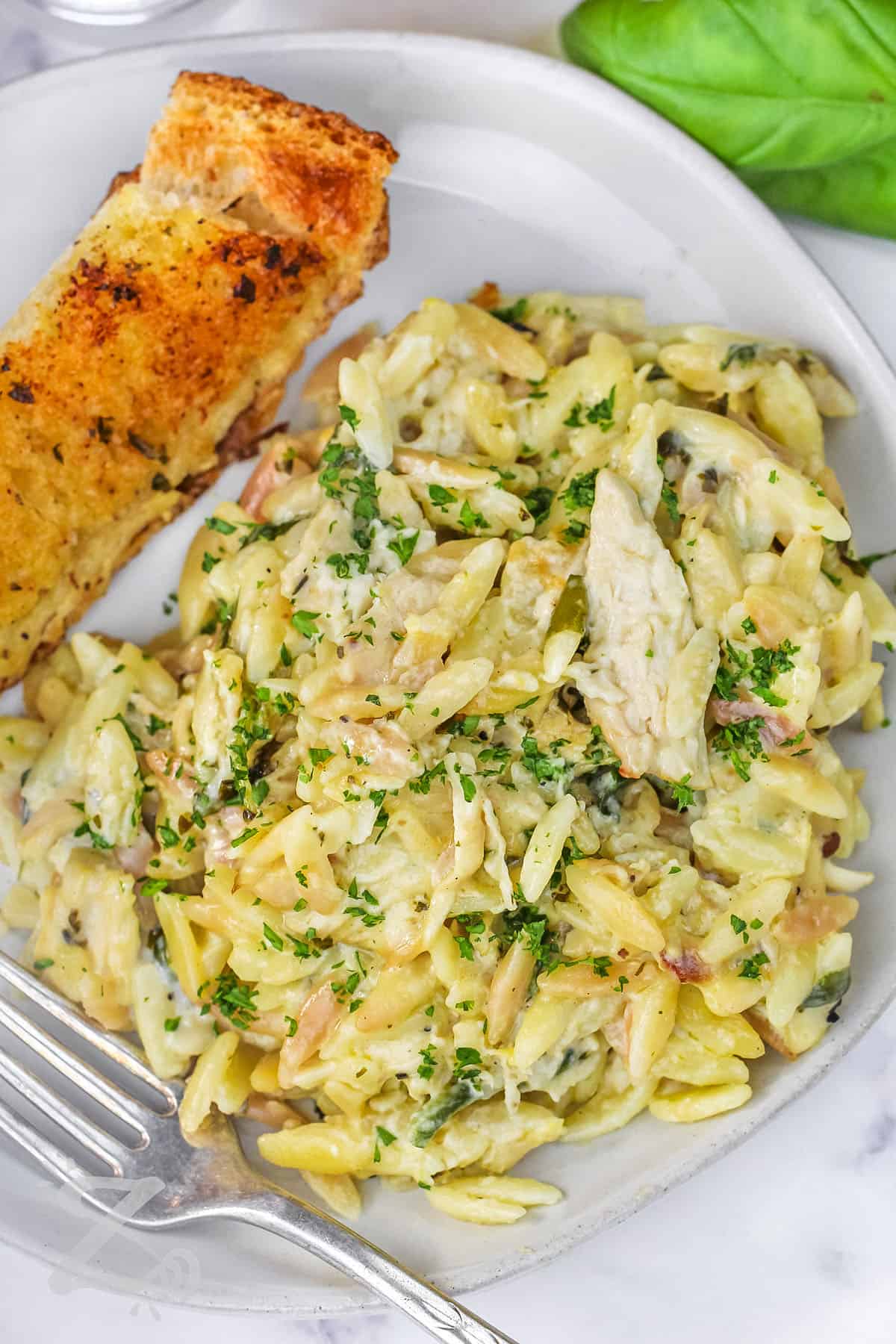 close up of Lemon Chicken Orzo on a plate with a piece of garlic toast