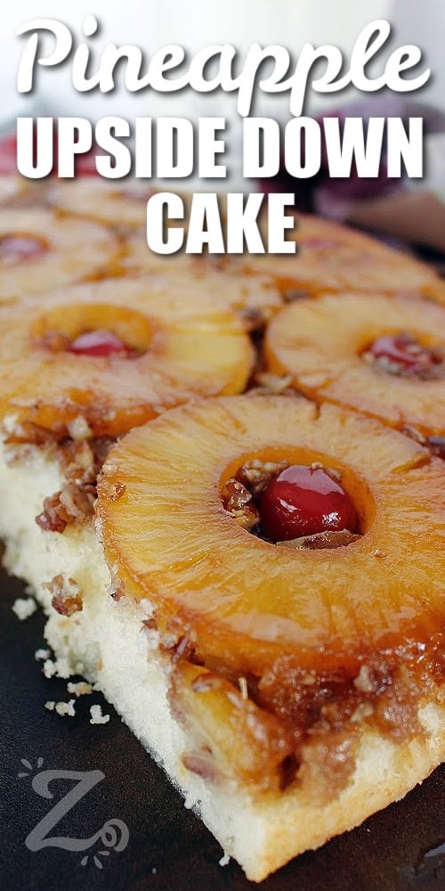 homemade pineapple upside down cake on a serving platter, with a slice taken out of it with a title