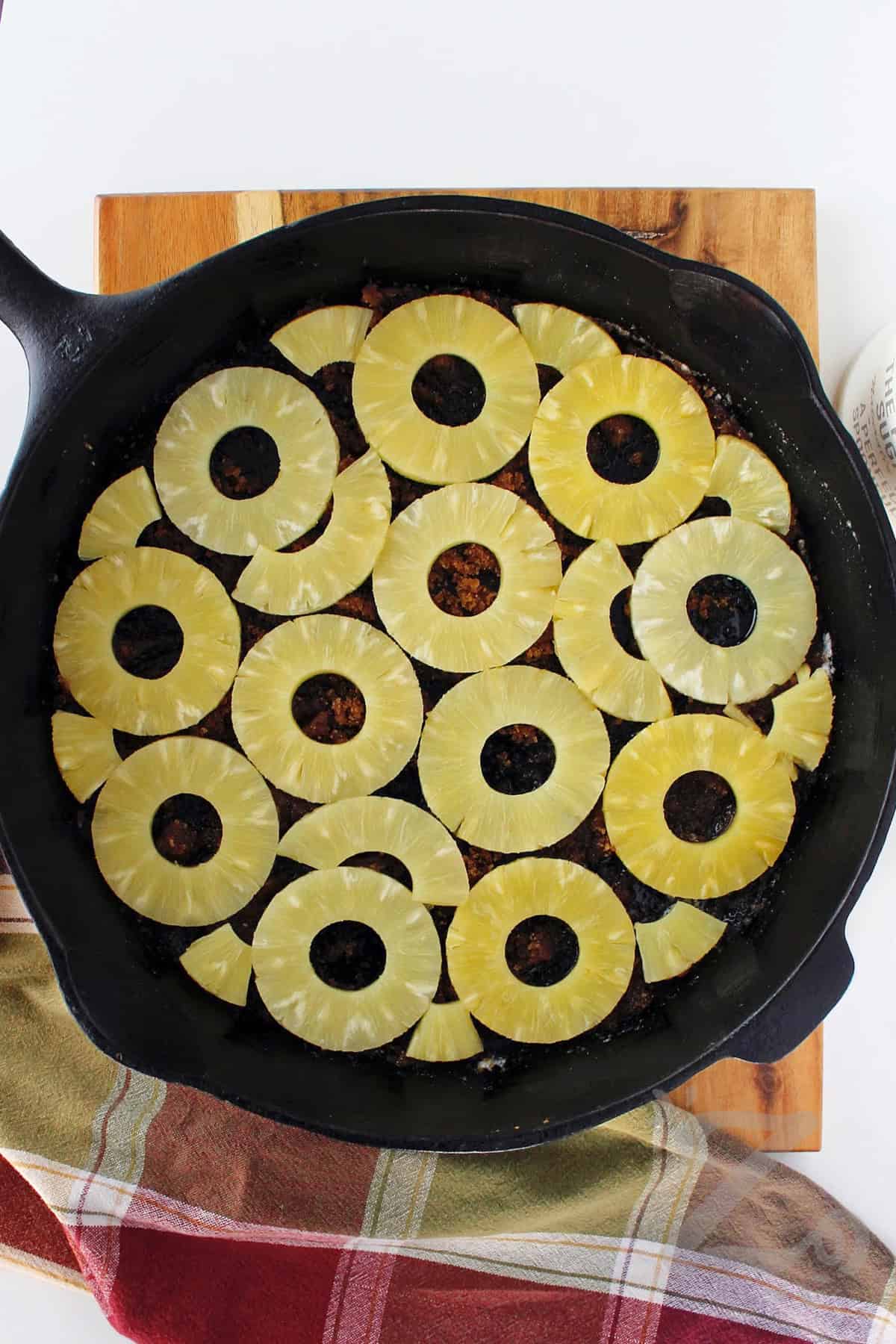 pineapple slices placed over the buttery brown sugar layer in a cast iron pan to make homemade pineapple upside down cake