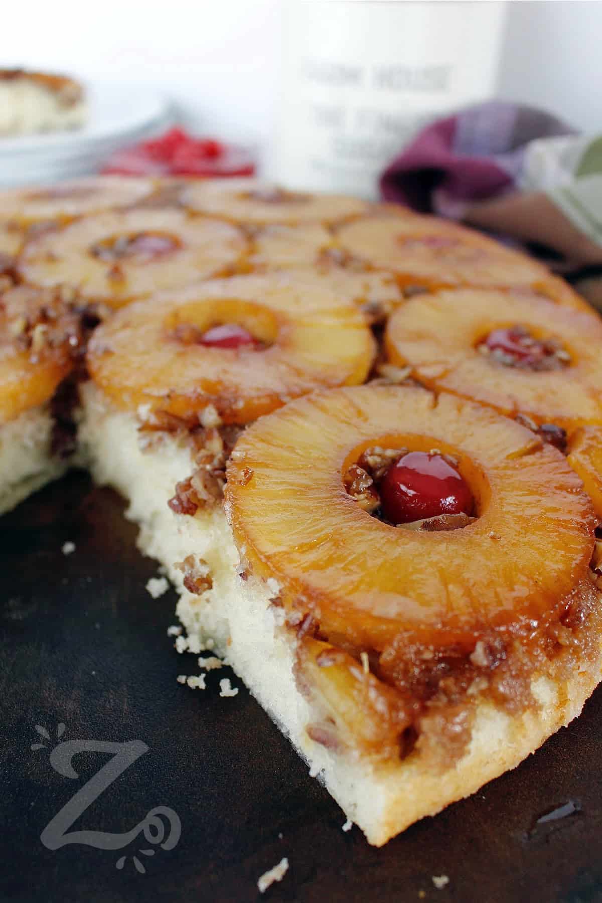 homemade pineapple upside down cake on a serving platter, with a slice taken out of it