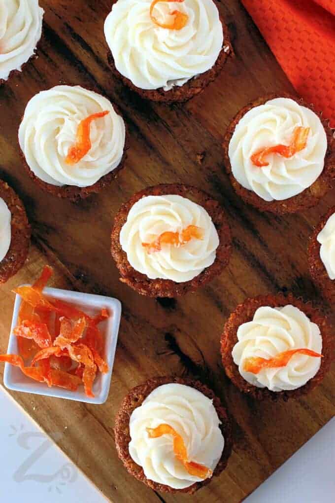 For the best results, avoid overmixing the batter—this helps keep the cupcakes soft and tender. Stir until just combined for the perfect texture. If adding walnuts or pecans, toast them first to enhance their nutty flavor. Always use a toothpick to check for doneness. The cupcakes should come out clean or with just a few crumbs. With these simple baking tips, your carrot cupcakes will turn out perfect every time. #ourzestylife carrot cupcakes on a wooden board garnished with candied carrots