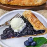 a slice of blueberry galette on a plate topped with ice cream