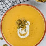 pumpkin soup in a bowl topped with seeds