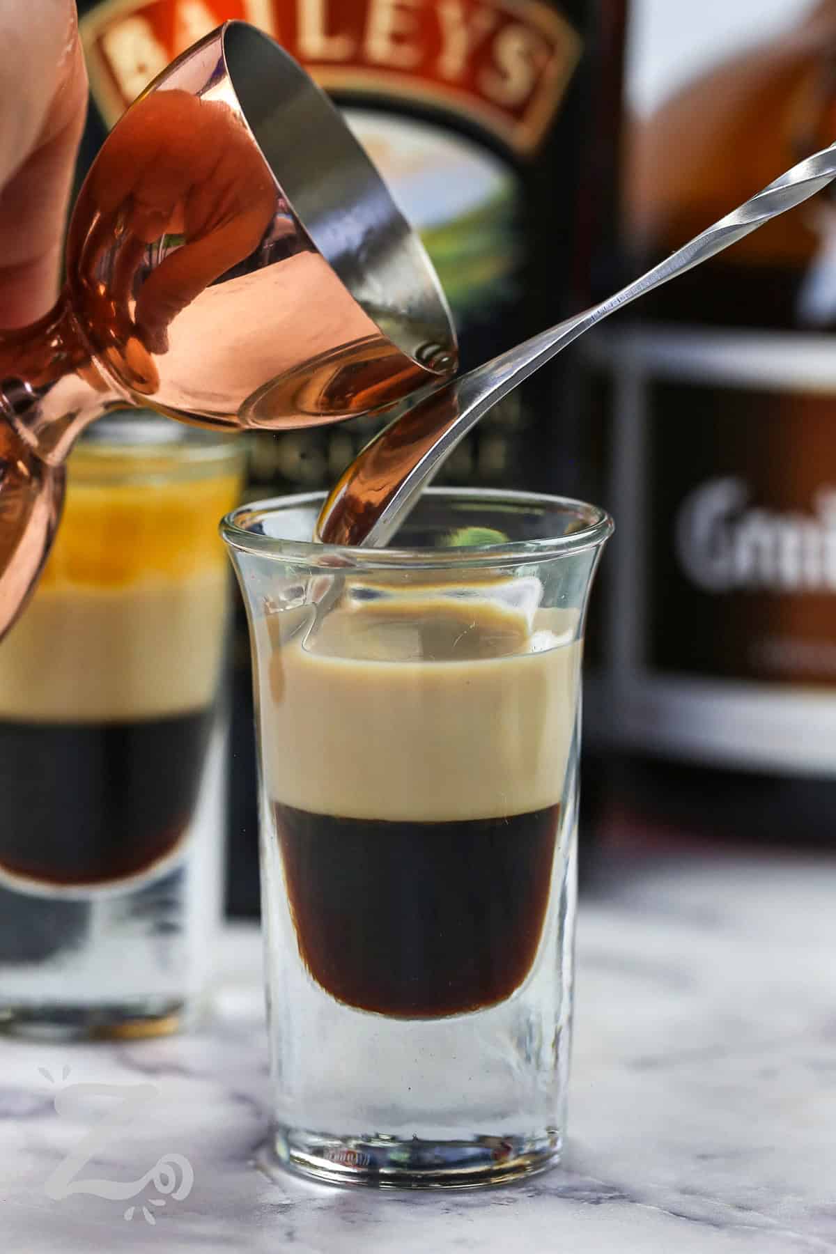 close up of adding orange liqueur to shot glass to make B52 Shot