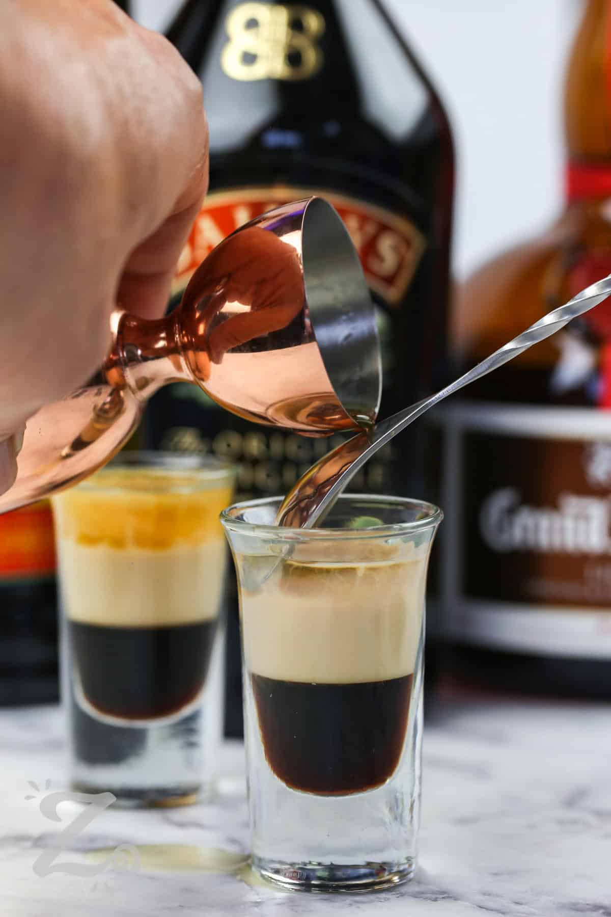 adding orange liqueur to shot glass to make B52 Shot