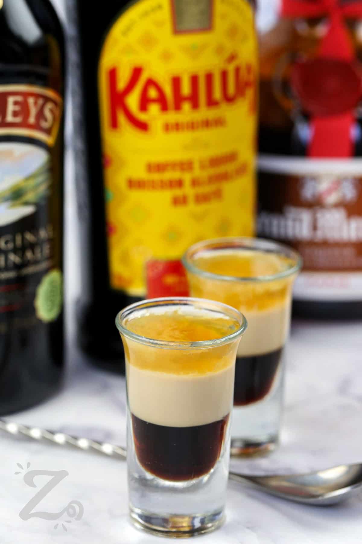 shot glasses of B52 Shot with liquor bottles in the back