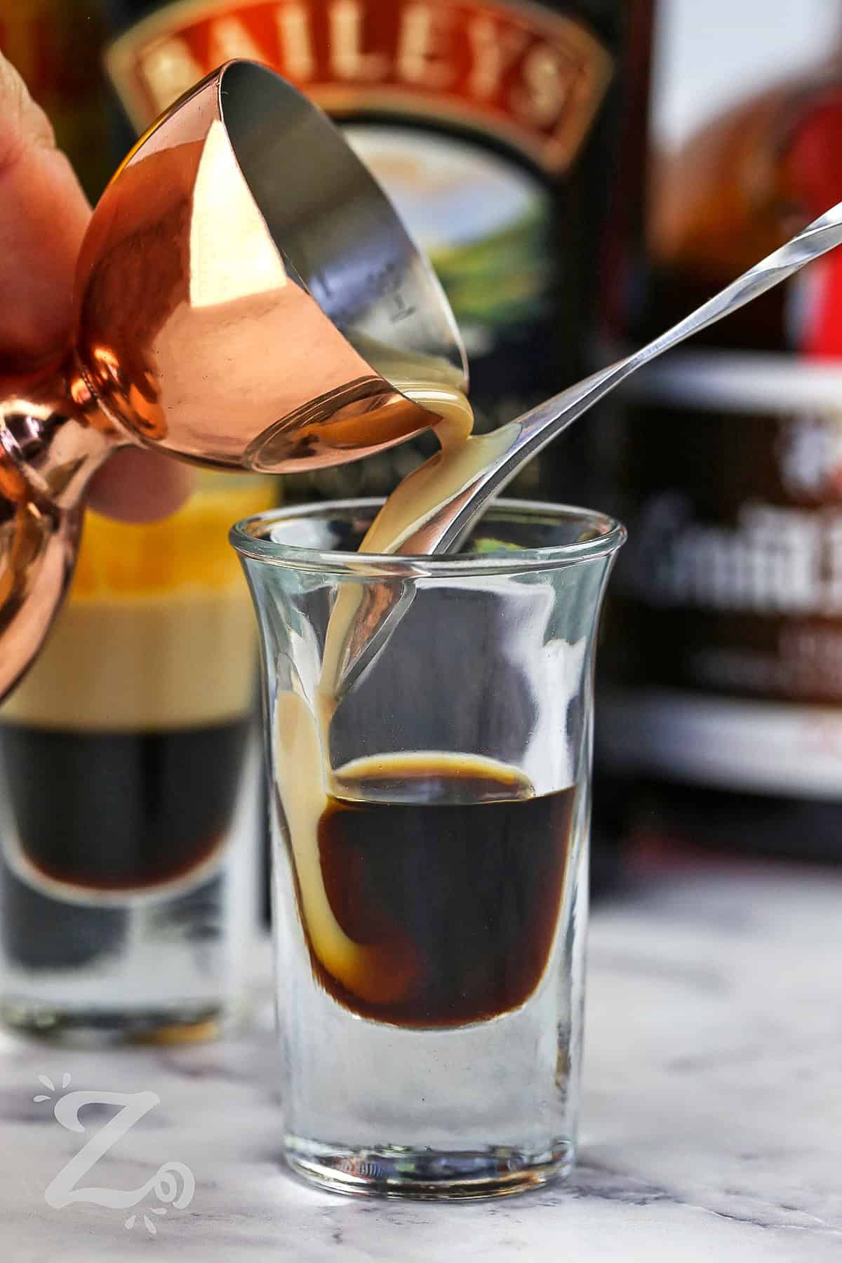 adding irish cream to shot glass to make B52 shot