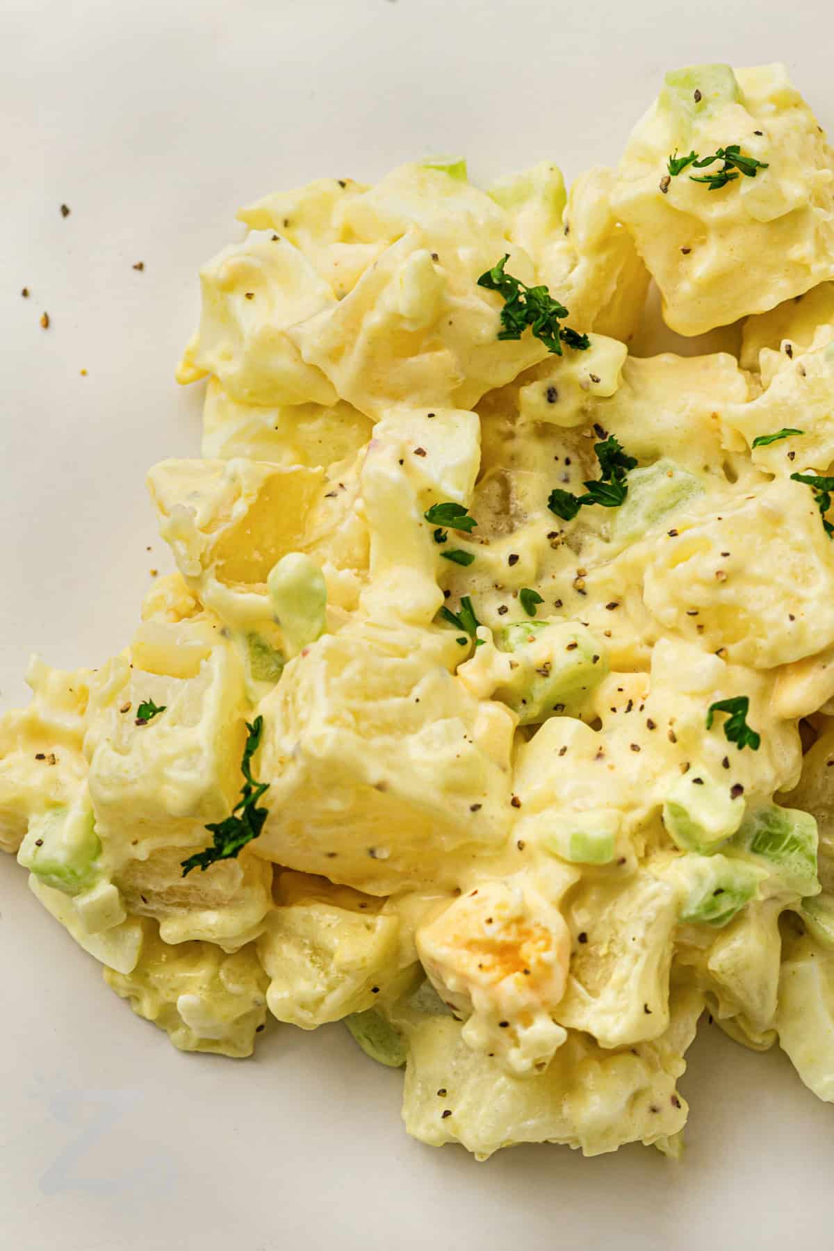 Classic potato salad recipe ideas are always welcome during barbecue and picnic season. This creamy potato salad combines potatoes, eggs, celery, and onion with a rich, flavorful mustard mayo dressing. It is a simple homemade side dish that tastes even better after chilling. Serve this cold potato salad with burgers, barbecue ribs, sandwiches, or grilled chicken. #ourzestylife Classic Potato Salad with salt and pepper