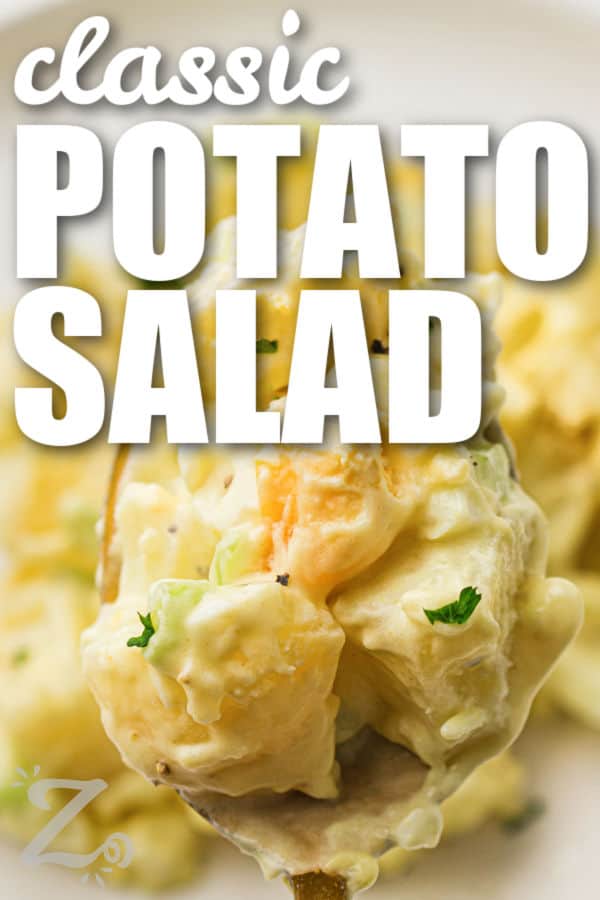 Classic potato salad recipe cravings are easy to satisfy with this creamy homemade favorite. Yukon Gold or red potatoes are mixed with eggs, celery, and onion in a rich mustard dressing that is full of savory taste. This old-fashioned potato salad is perfect for family cookouts, holiday meals, and backyard barbecues. Keep it chilled and serve it with grilled meats or deli sandwiches. #ourzestylife spoon full of Classic Potato Salad with a title