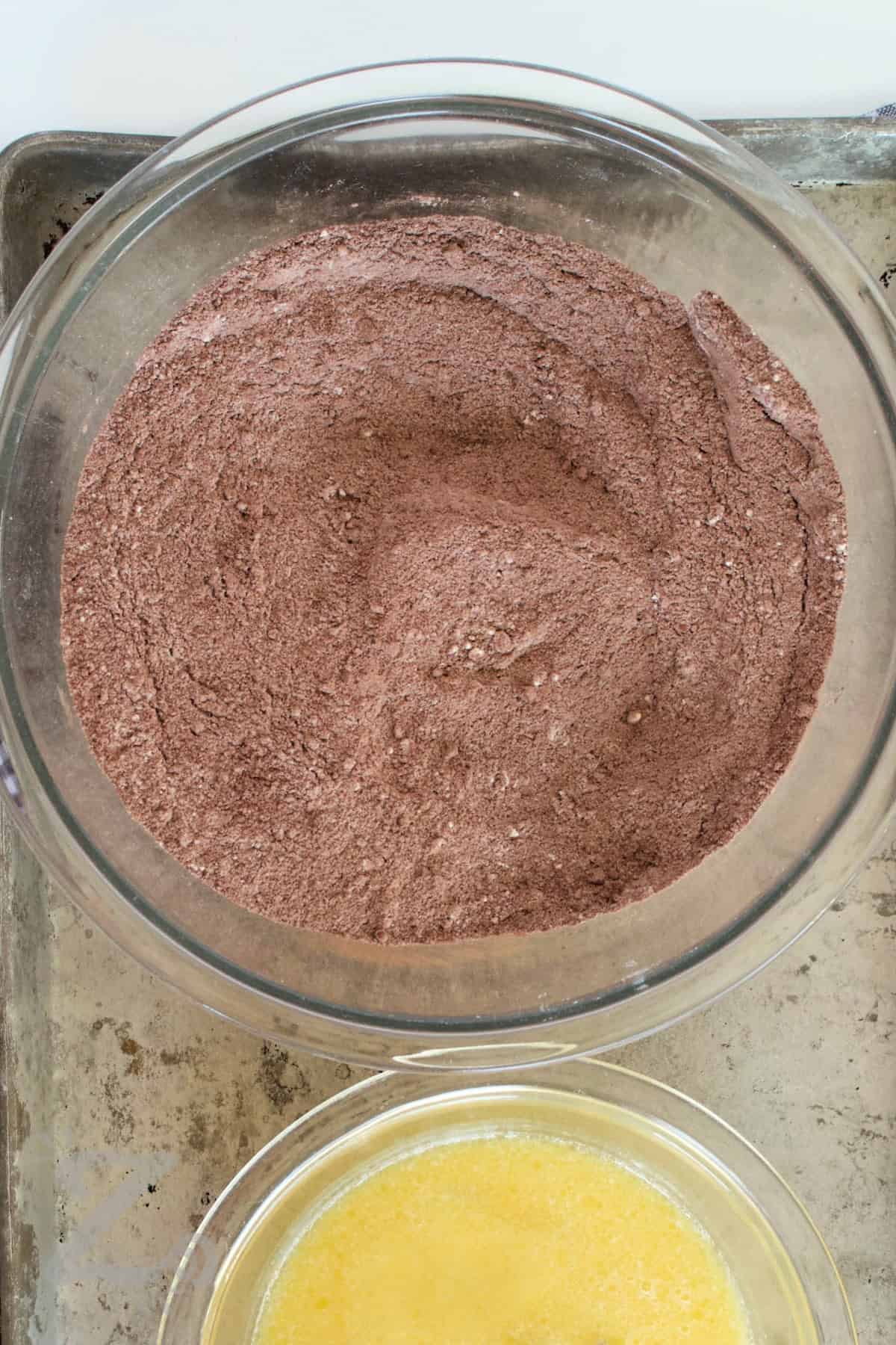 This moist cake is made with simple pantry ingredients and comes together in just a few steps. The result is a soft, rich cake with a tender crumb and bold chocolate flavor that tastes like it came from a bakery. Why not try this homemade chocolate cake recipe? #ourzestylife process to make homemade chocolate cake with dry ingredients and wet ingredients in two bowls