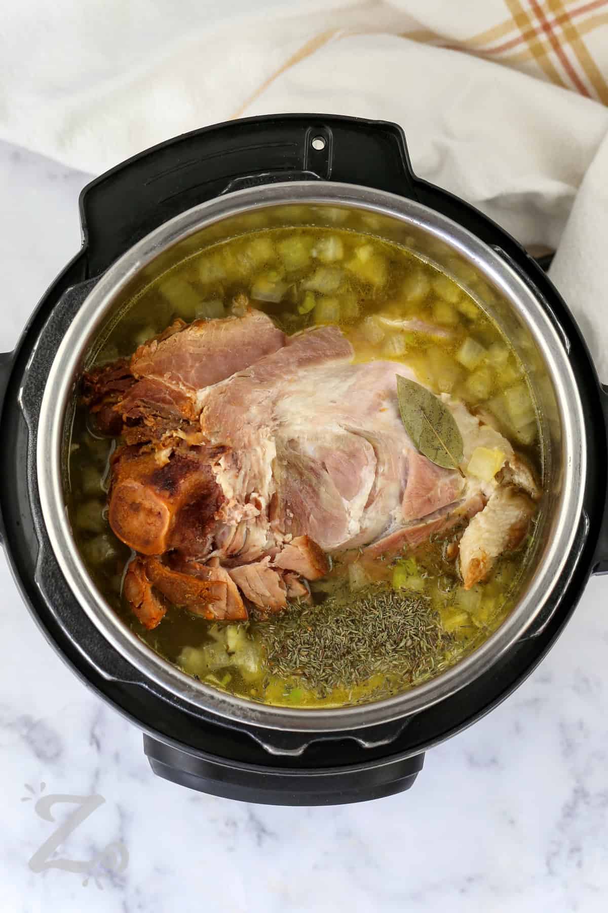 Instant Pot split pea soup turns simple pantry ingredients into a rich and hearty homemade meal. Smoky ham, creamy peas, and tender vegetables create comforting flavor in every spoonful. This pressure cooker soup recipe is perfect for chilly nights when you want something warm, filling, and satisfying for dinner. It is easy enough for busy evenings while still tasting like classic homemade comfort food. Try this hearty family dinner recipe tonight. #ourzestylife adding ingredients to pot to make Instant Pot Split Pea Soup with Ham