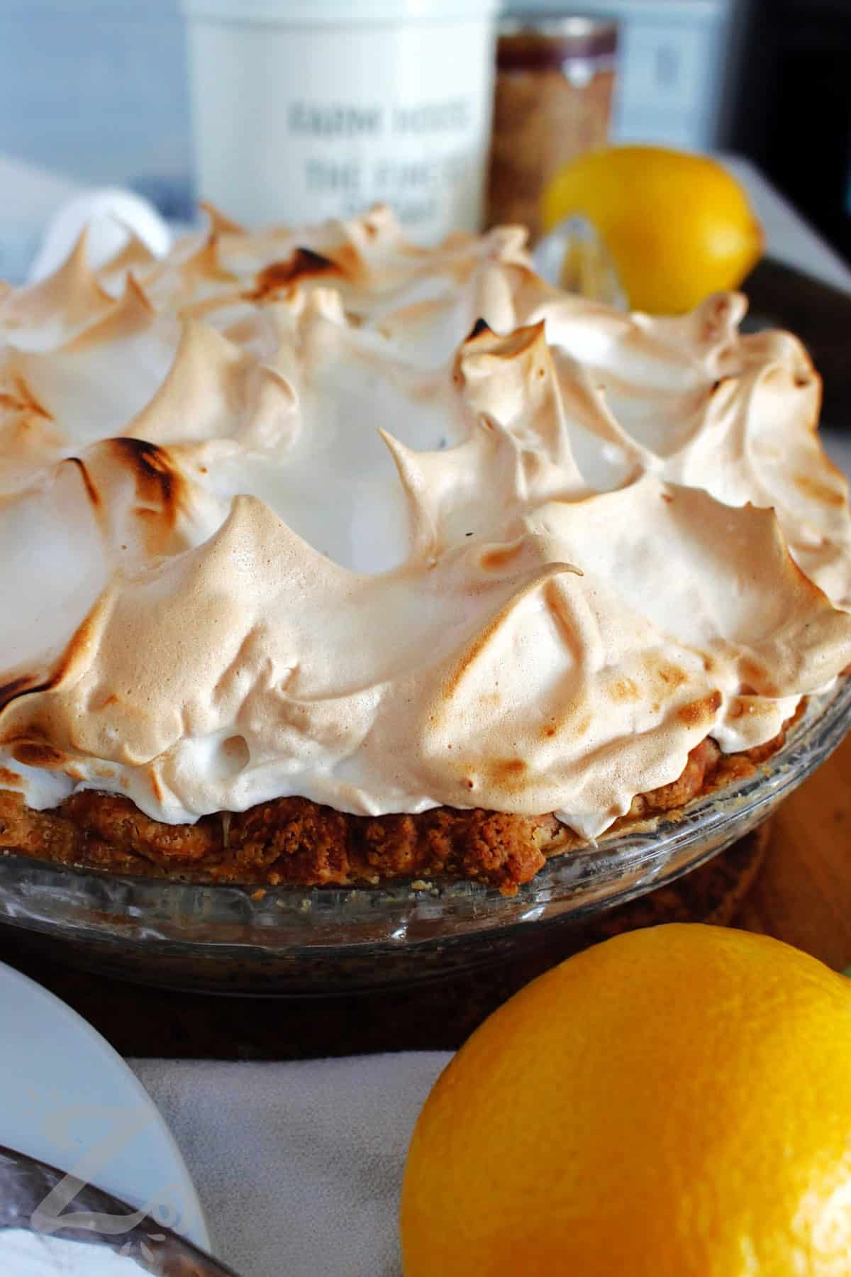 a whole baked lemon meringue pie with a lemon on the side