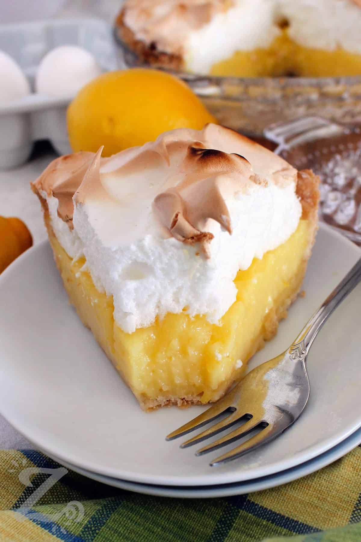 a slice of lemon meringue pie with forkful bitten out of it