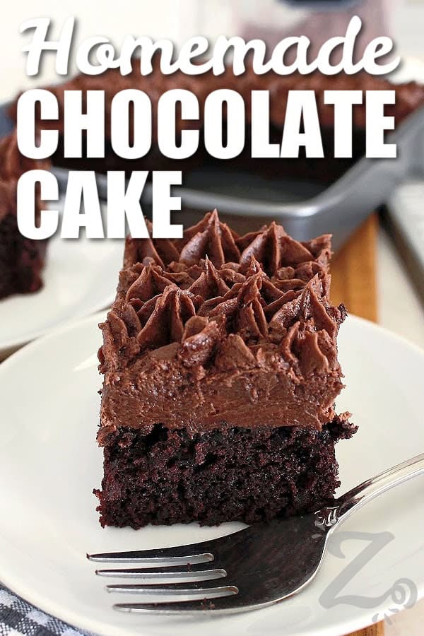 This homemade chocolate cake is proof that simple ingredients can create something extra special. It is rich, moist, deeply chocolatey, and wonderfully easy to make. Whether you serve it frosted for celebrations or plain with a cup of coffee, this cozy cake recipe is one you will find yourself returning to again and again. Make it for your next casual dinner at home. #ourzestylife a slice of homemade chocolate cake on a white plate with a fork, with a title