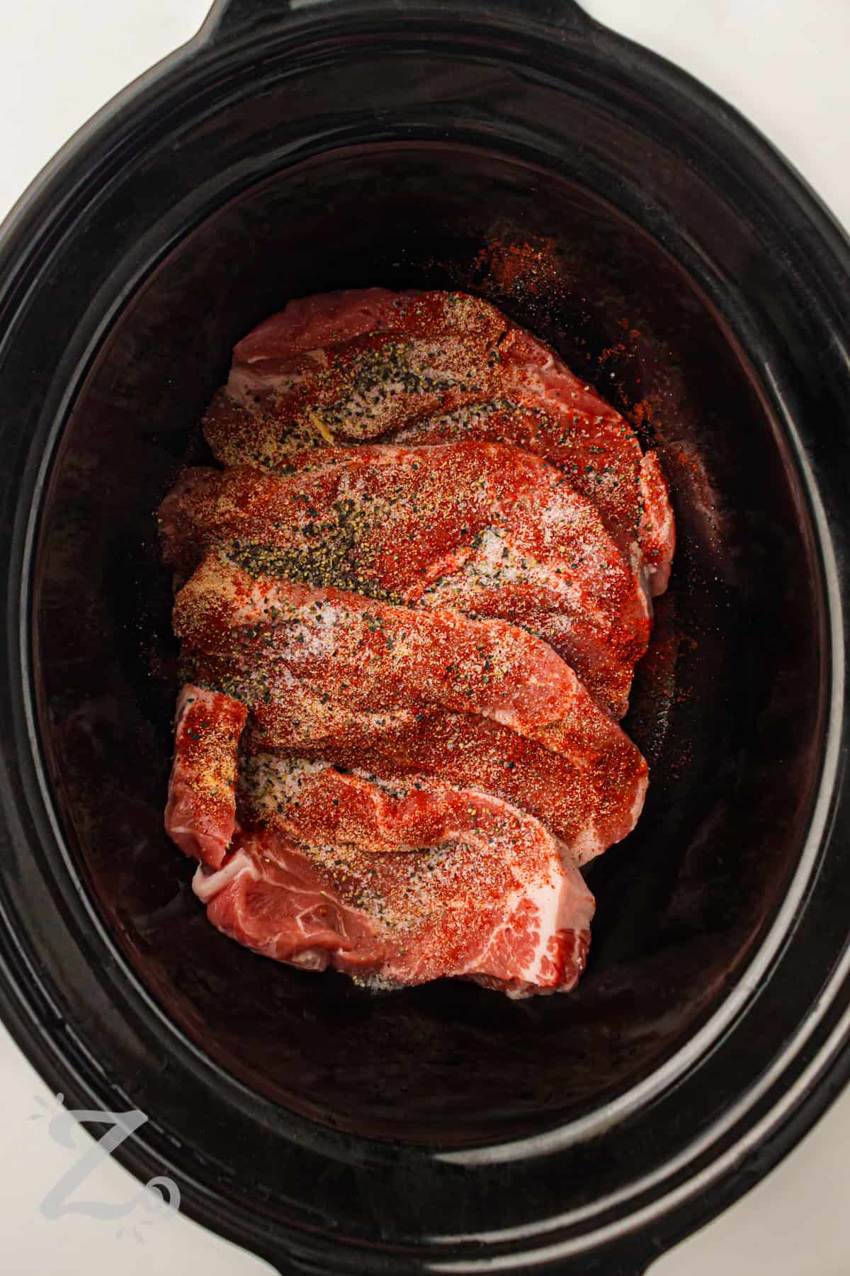 adding seasonings to pork to make Slow Cooker BBQ Pulled Pork