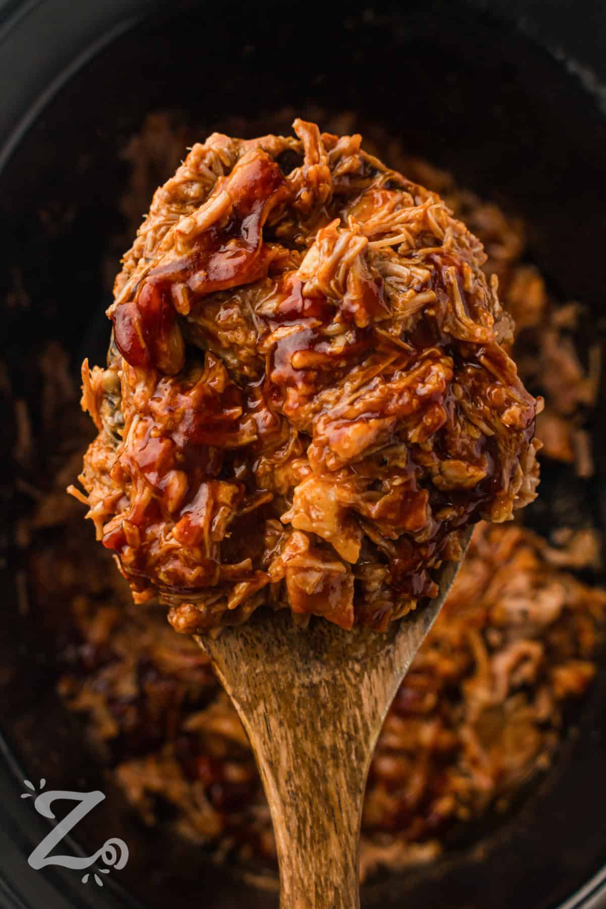 taking a spoonful of Slow Cooker BBQ Pulled Pork out of the pot