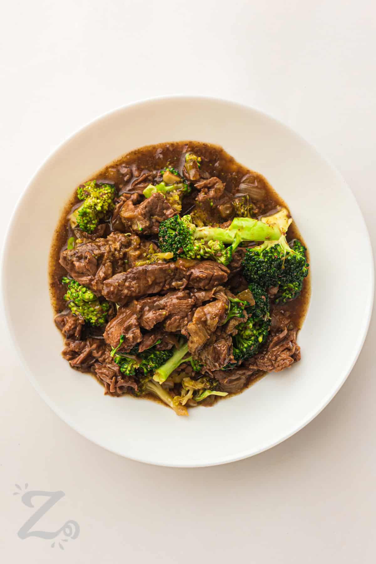 Slow cooker beef and broccoli makes meal planning easier with a simple Crockpot method. It brings together beef, broccoli, garlic, and soy sauce for a rich and savory dinner. The flavors blend as it cooks, creating a sauce that coats every bite. This recipe is great for leftovers and meal prep lunches. Try it for your next family meal and serve it warm with rice. #ourzestylife plated Slow Cooker Beef and Broccoli