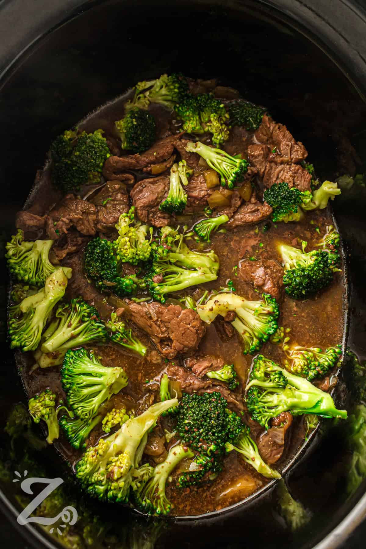 Slow cooker beef and broccoli brings tender beef and broccoli together in a rich, savory garlic soy sauce. It is an easy way to enjoy a homemade takeout-style dinner with simple pantry ingredients. The sauce blends soy, garlic, onion, and a touch of sweetness for deep flavor. Serve it over rice or noodles for a full meal that feels hearty and satisfying. Make it tonight for an easy family dinner and enjoy every bite. #ourzestylife pot full of Slow Cooker Beef and Broccoli