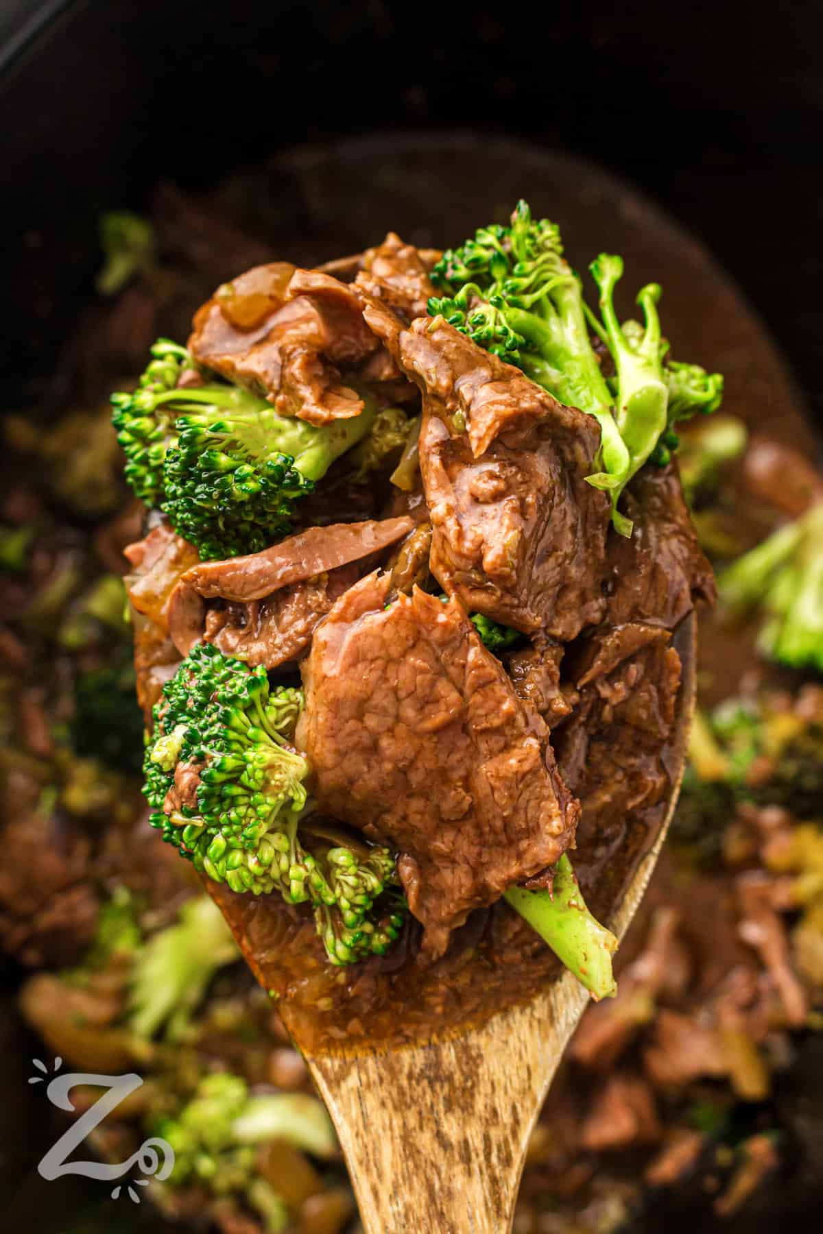 Slow cooker beef and broccoli is a satisfying meal with bold, savory flavor in every bite. The beef becomes fork-tender while simmering in a garlic soy sauce blend. A touch of sweetness balances the sauce for a takeout-style finish. It is perfect for serving over rice or noodles for a complete dinner. Try it tonight and enjoy a simple homemade meal. #ourzestylife close up of Slow Cooker Beef and Broccoli on a spoon