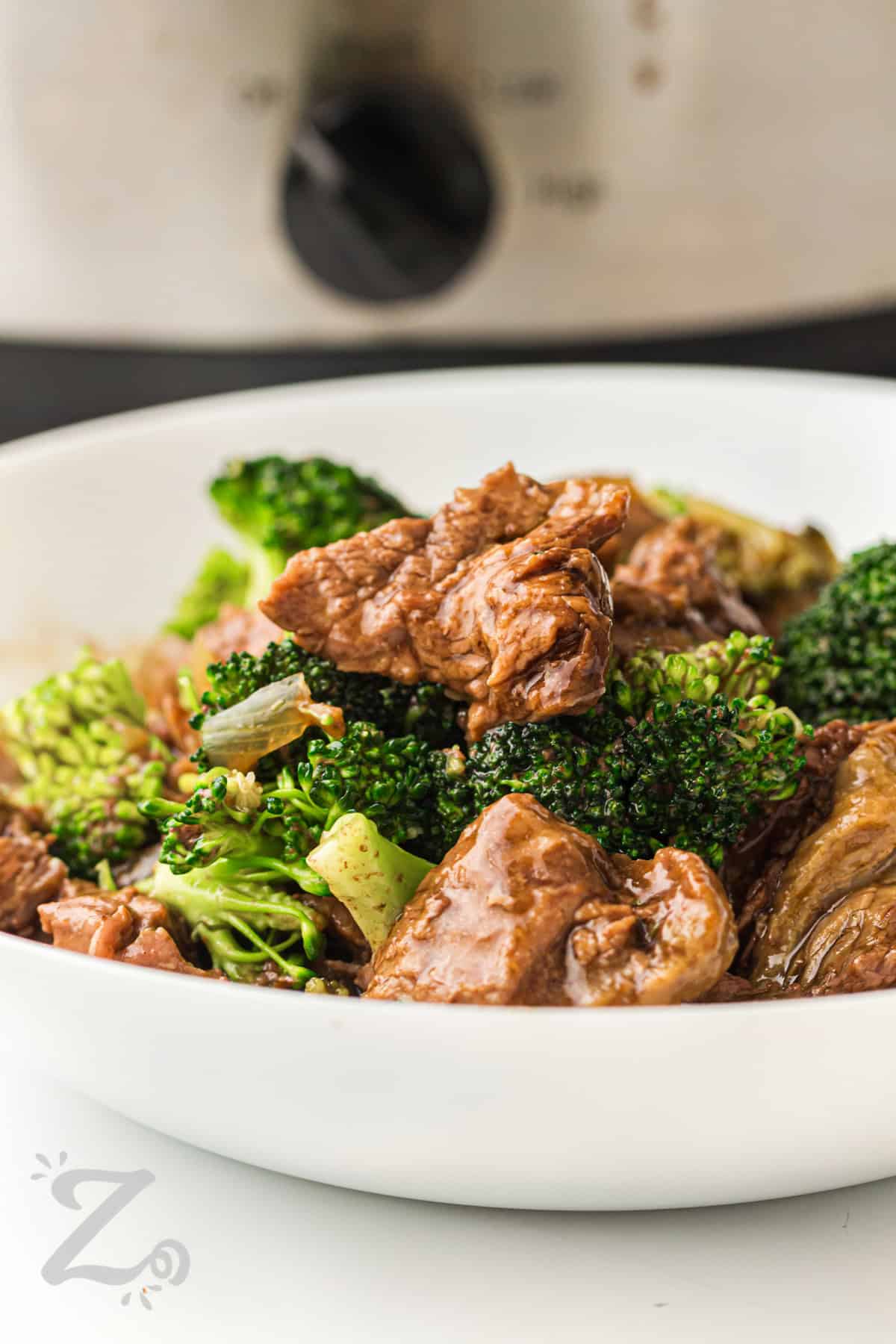 Slow cooker beef and broccoli delivers a hearty dinner that tastes like classic takeout. It uses simple pantry staples to create a rich and flavorful sauce. The slow cooker does all the work while the beef becomes tender and juicy. This dish pairs perfectly with rice or noodles for a complete meal. Cook it for dinner and enjoy an easy family favorite. #ourzestylife plated dish of Slow Cooker Beef and Broccoli