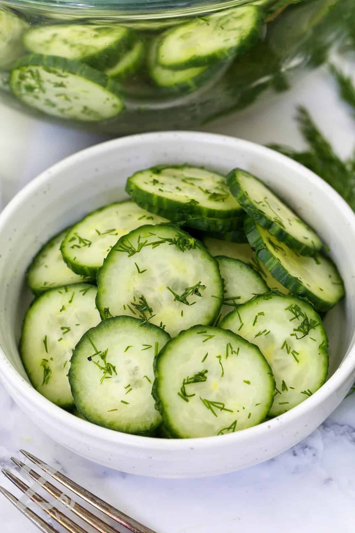 Enjoy this easy cucumber salad whenever you need a refreshing side dish. The crisp cucumbers and fresh dill are tossed with a light vinegar dressing that brings bright flavor to every bite. It is a delicious choice for BBQs, picnics, potlucks, and everyday dinners with your favorite grilled foods. Give this recipe a place on your table. #ourzestylife close up of Easy Cucumber Salad
