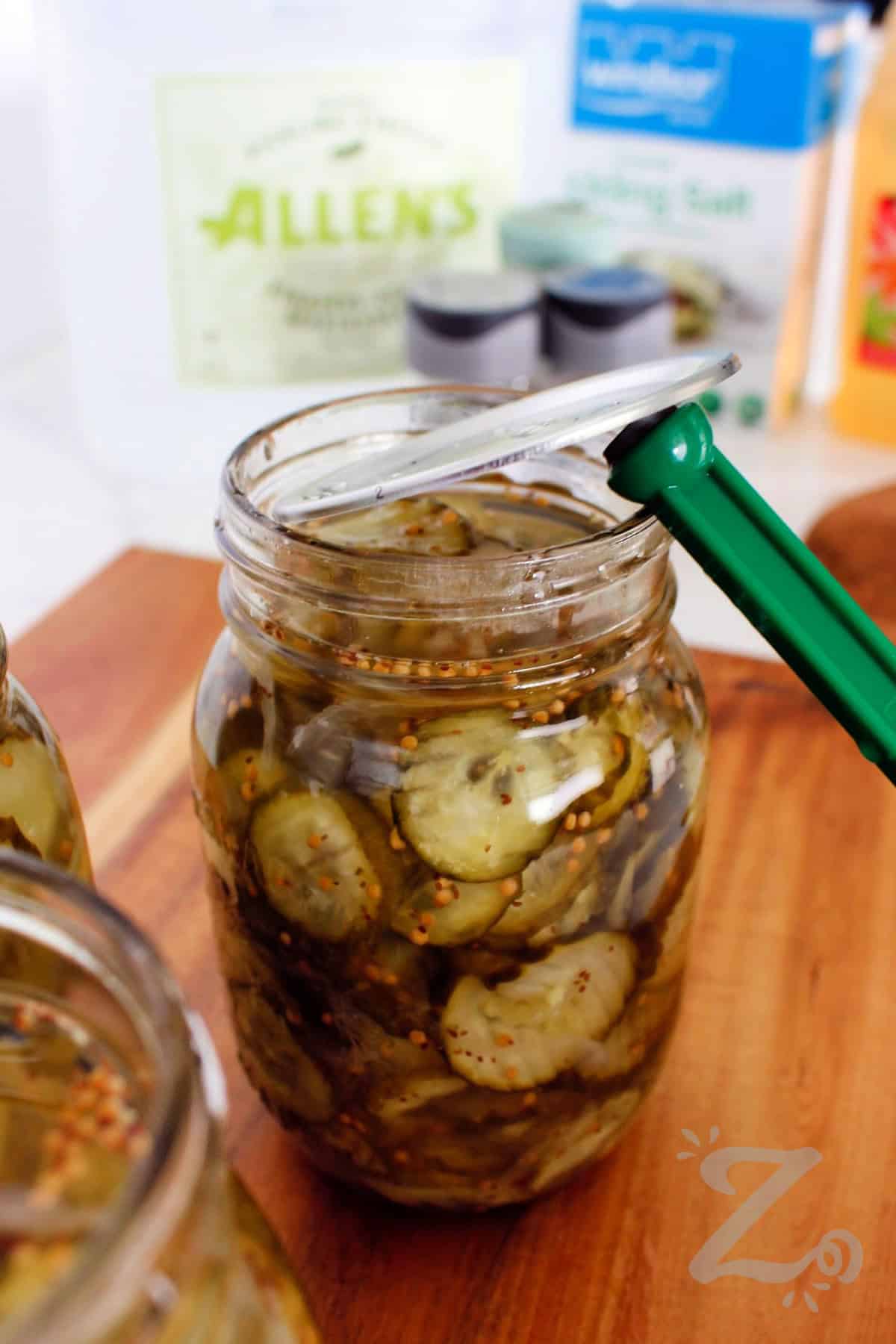 This home style Bread and Butter Pickles recipe is easy to make. The sliced cucumbers transform into sweet, tangy, and deliciously crunchy pickles. So no matter if you're preserving garden cucumbers or stocking your pantry, these bread and butter pickles are simple to make and taste even better after a day or two in the brine. Why not give this recipe a try this summer? #ourzestylife process to make bread and butter pickles recipe putting the lid on the mason jar