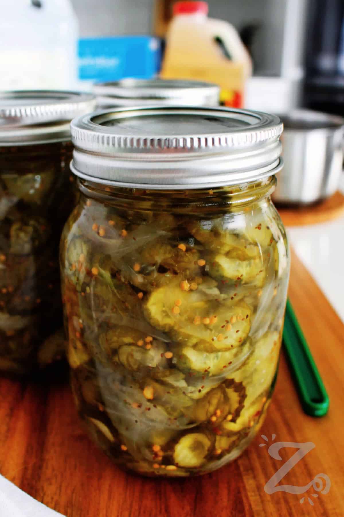 Add homemade flavor to every meal with this simple Bread and Butter Pickles recipe! Sweet, tangy, and loaded with crunchy cucumbers and onions, they're the perfect topping for burgers, sandwiches, wraps, and even cheese boards. Using just a few ingredients and simple instructions, you can choose between short storage refrigerator pickles, or make the canned version for longer pantry storage. #ourzestylife bread and butter pickles recipe sealed in a mason jar