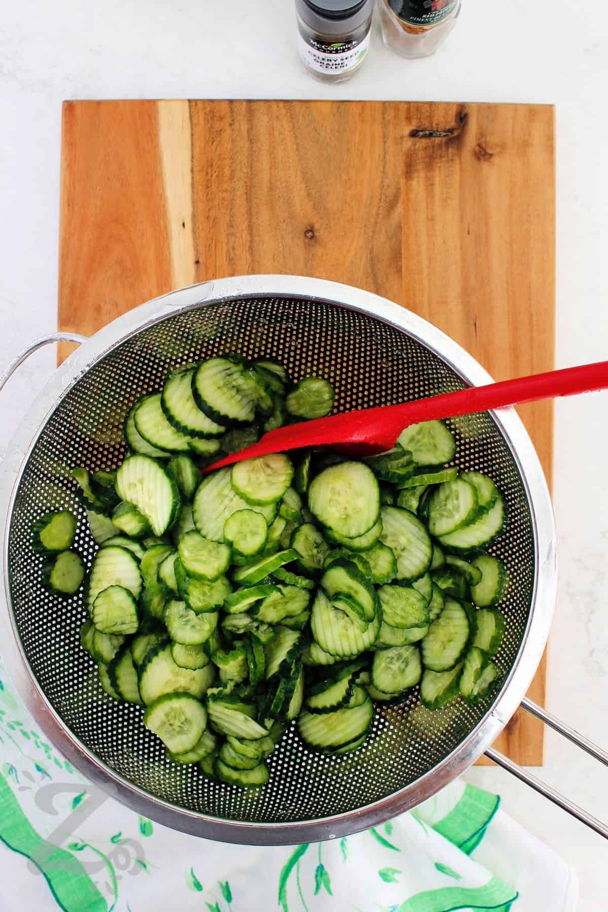 Add sweet and tangy flavor to every meal with this Bread and Butter Pickles recipe! Loaded with crunchy cucumbers and onions, these pickles make the perfect topping for burgers, sandwiches, wraps, and even cheese boards. Using just a few ingredients and simple instructions, you can choose between short storage refrigerator pickles, or make the canned version for longer pantry storage. #ourzestylife process to make bread and butter pickles recipe after cucumbers have been drained and rinsed