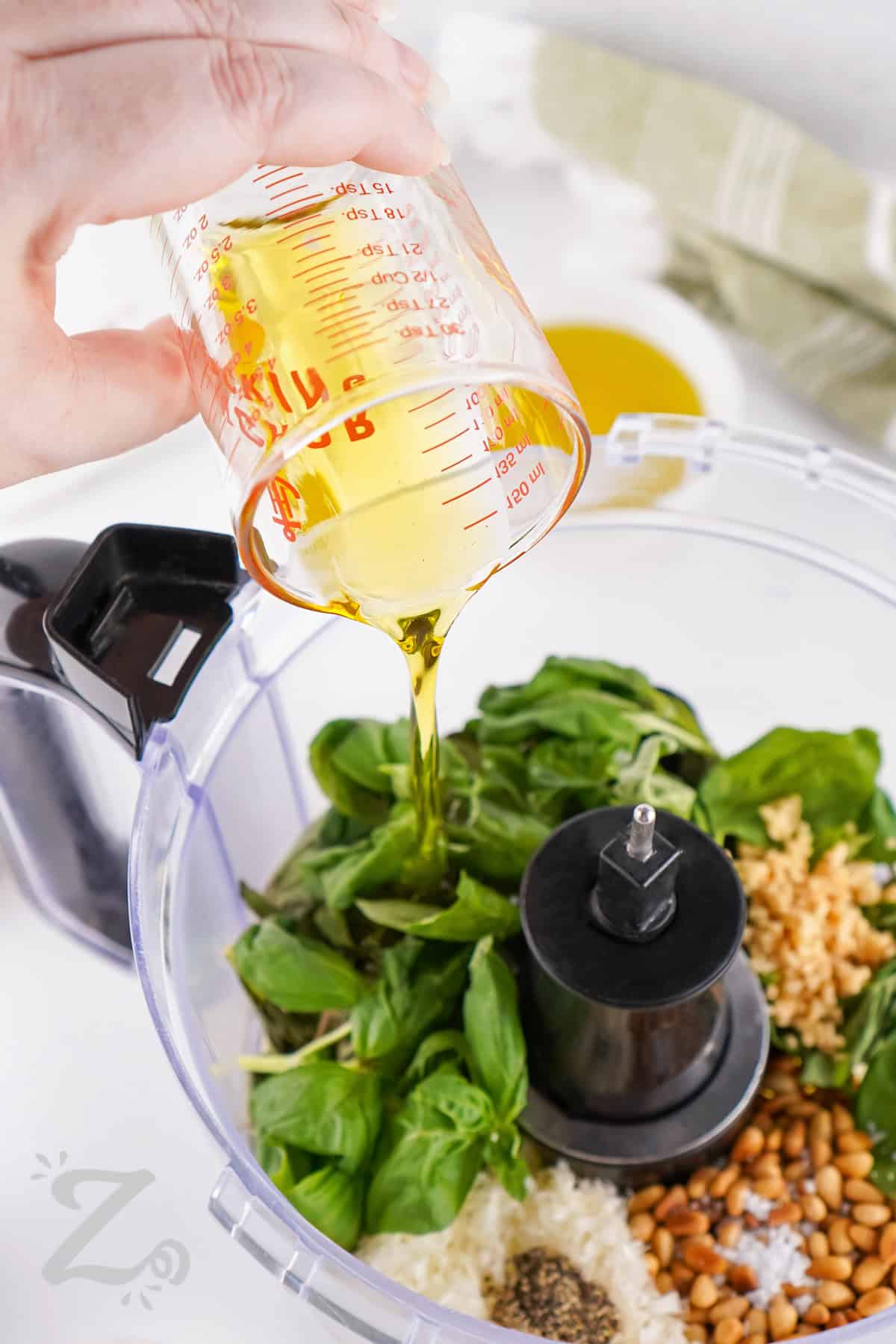 adding ingredients to food processor to make Homemade Pesto