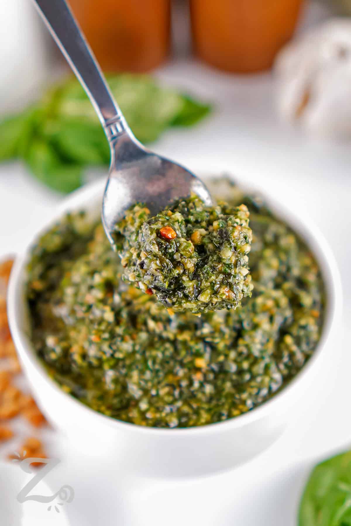 taking a spoonful of Homemade Pesto out of the bowl