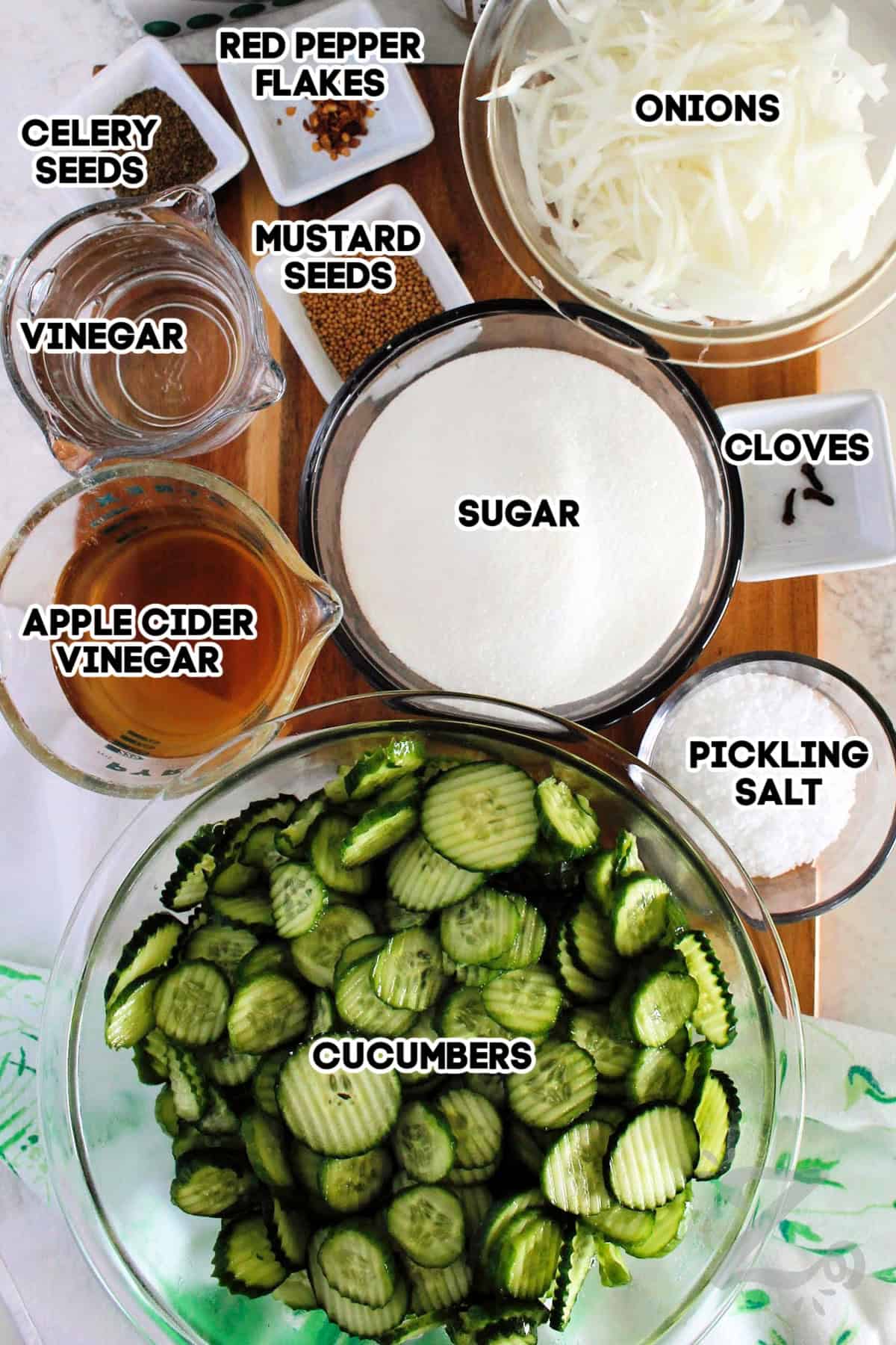 If you love sweet pickles with plenty of crunch, you'll love this Bread and Butter Pickles recipe. Made with simple pantry ingredients, these homemade pickles are perfect for canning, gifting, or enjoying straight from the jar. Why not make some with your fresh garden cucumbers this summer? #ourzestylife celery seeds, red pepper flakes, onions, cloves, sugar, pickling salt, cucumbers, apple cider vinegar, vinegar, and mustard seeds assembled to make bread and butter pickles recipe