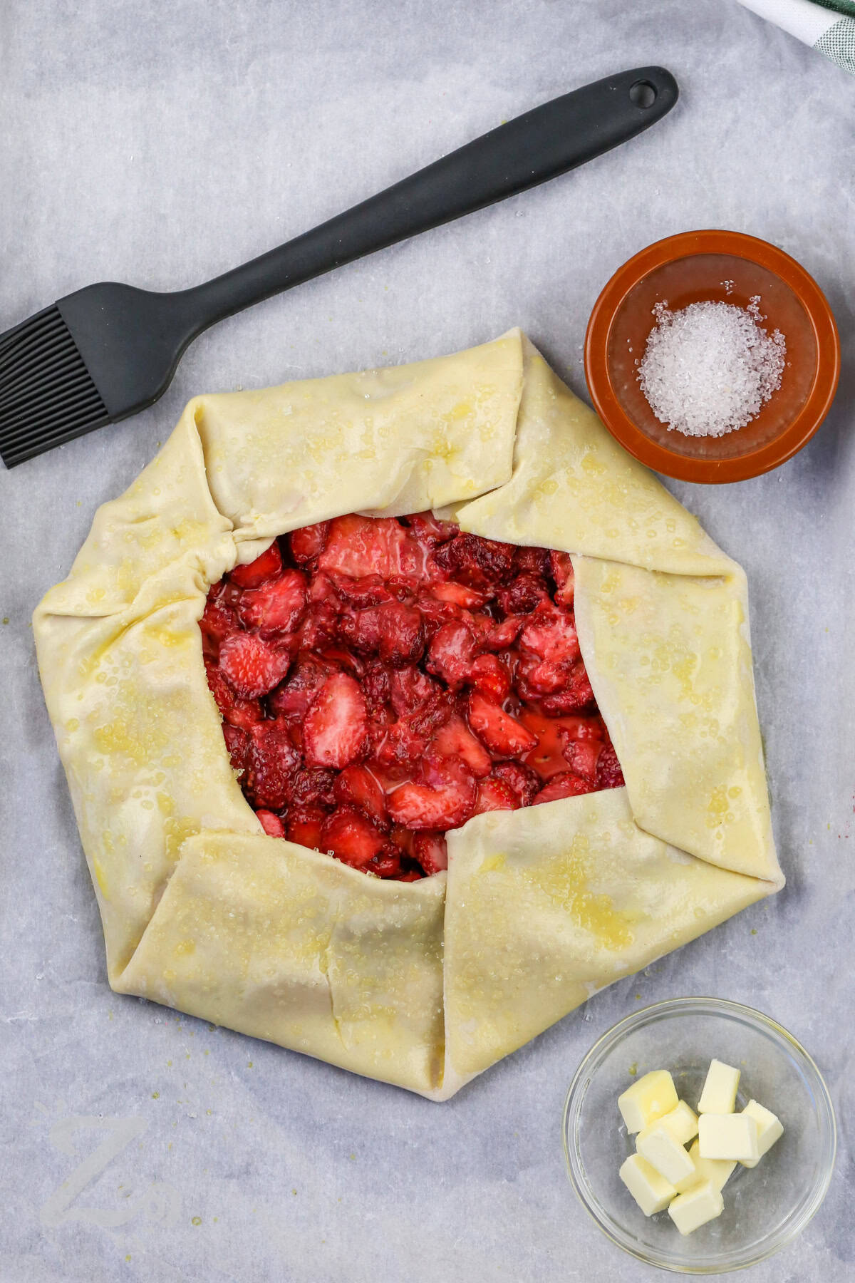 adding egg wash and sugar to Strawberry Galette